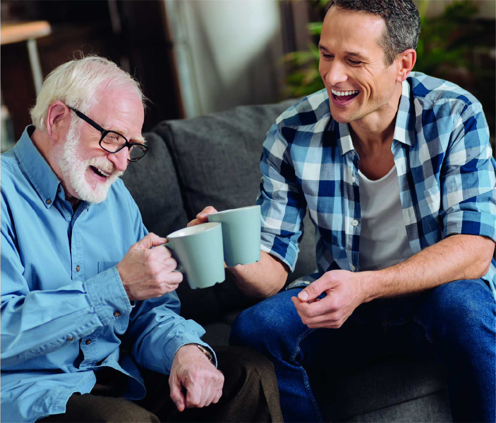 An elderly father and his middle-aged son enjoying a freshly-vended coffee at a residential care home.